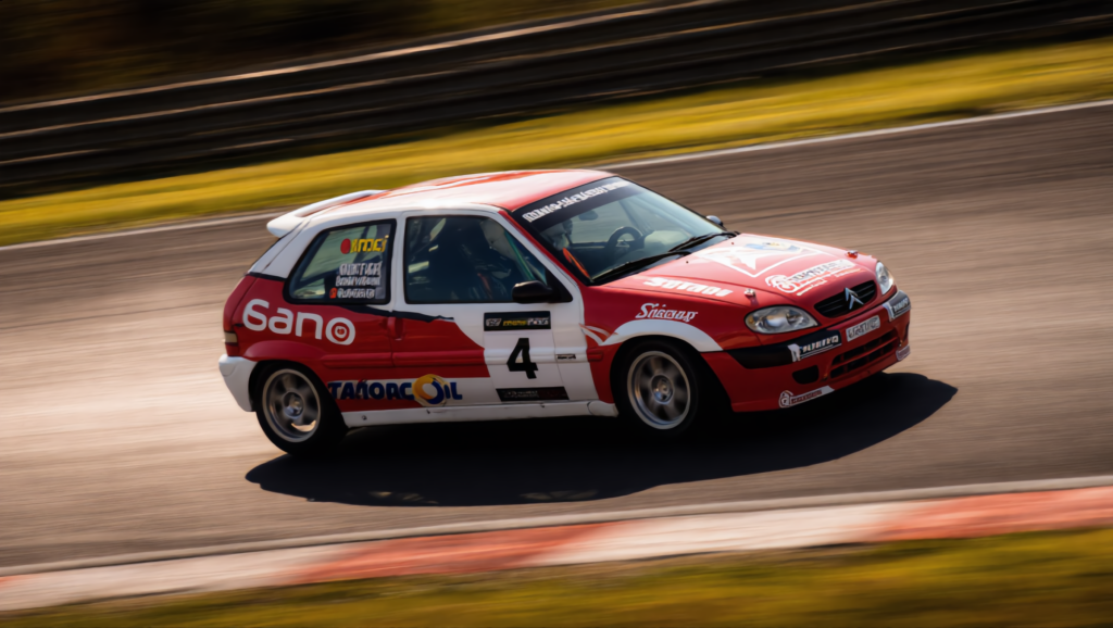 Coche de carreras rojo y blanco con número 4 en giro cerrado en pista
